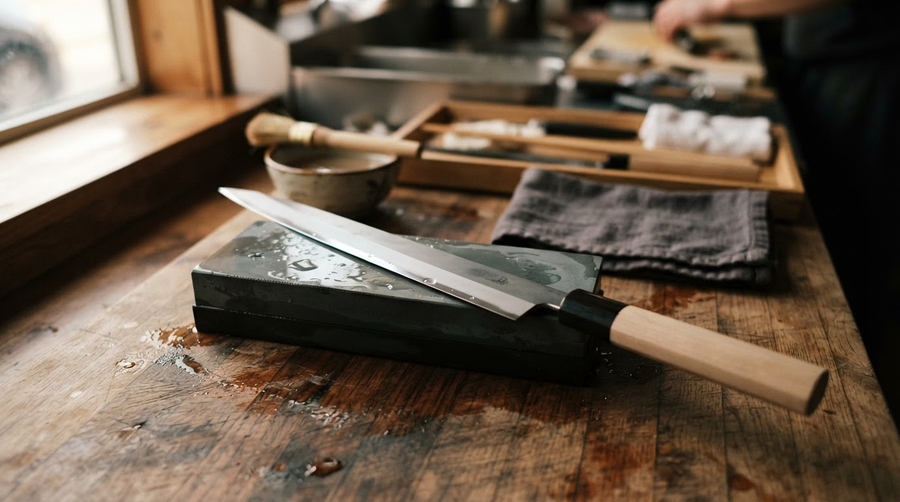 Yanagiba sushi knife resting on a wet whetstone, ready for sharpening single bevel knives